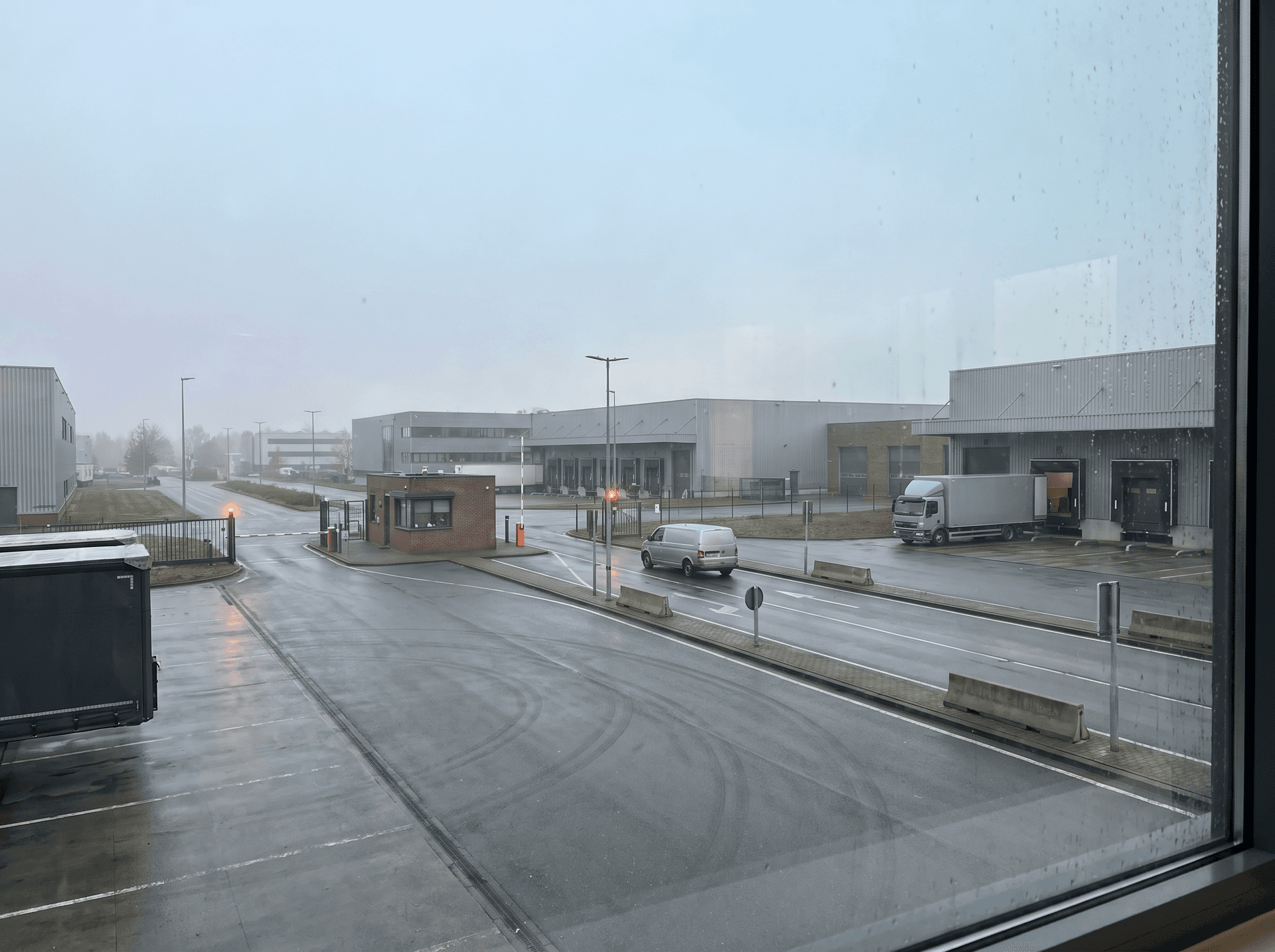 Logistikdepot mit Zufahrt und wenigen Fahrzeugen als ruhige Betriebsszene